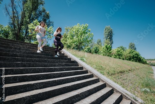 Foto Women exercising together outdoors, descending concrete steps during their workout under clear skies and vibrant greenery