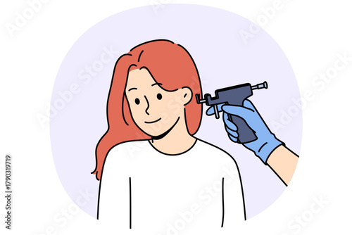 Machine for piercing ears near head of woman visiting cosmetologist to get opportunity to wear earrings. Girl is piercing ears with master, wanting to become beautiful and decorate image with jewelry