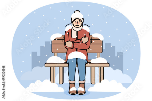 Freezing man sits on bench covered with snow due to lack of home and homeless shelters. Freezing guy is shaking and experiencing chills and needs social assistance to avoid getting sick.