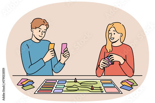 Happy couple playing board game while spending free time together and having fun after working day. Positive men and girl compete in board game, allowing them to get closer and improve mood