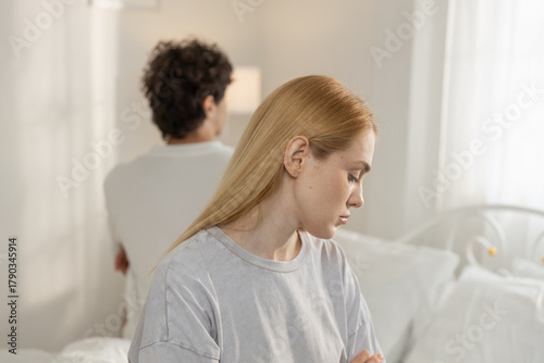 Quadro su tela Sad couple sitting on bed facing away from each other, showing emotional distance and relationship conflict