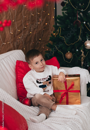 a little boy playing near a Christmas tree
