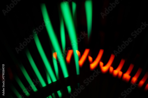 Abstract glowing green and red neon light patterns against a dark background.