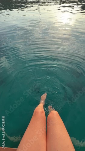 Woman feet splashing in clear water to the scenic view of a coastal lagoon and rising sun. Peaceful sunrise moment captured during a seaside escape.