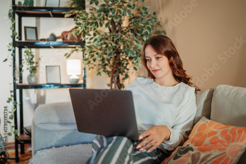 Young caucasian woman working or talking on laptop from home