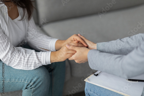 Foto A psychotherapist supports a young woman experiencing depression by holding her hands in a clinic