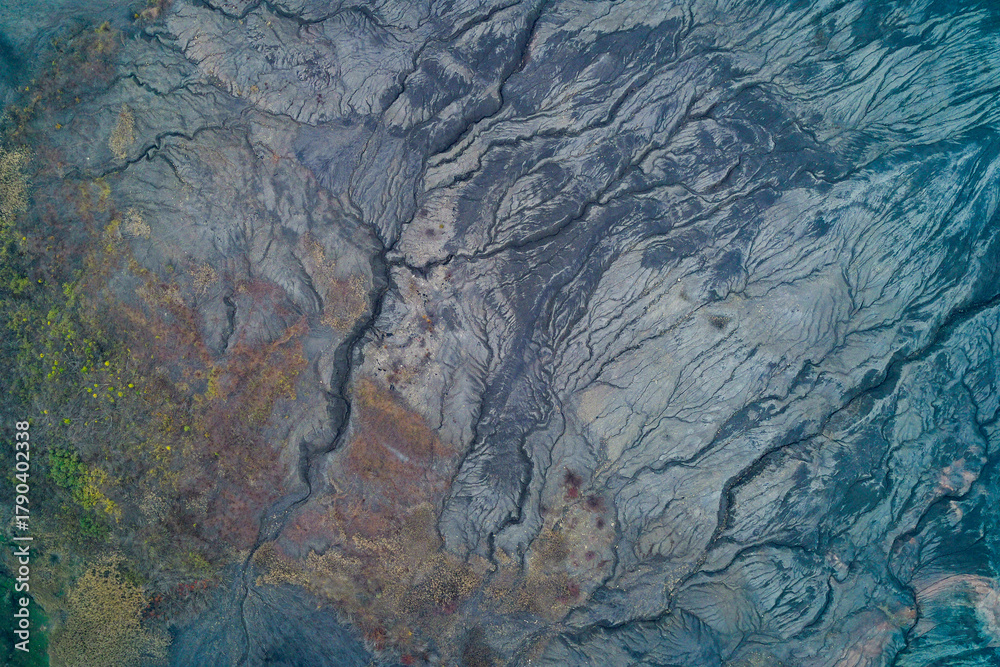 Naklejka premium Drone view of mineral-rich terrain with cracked earth and erosion lines forming organic abstract shapes