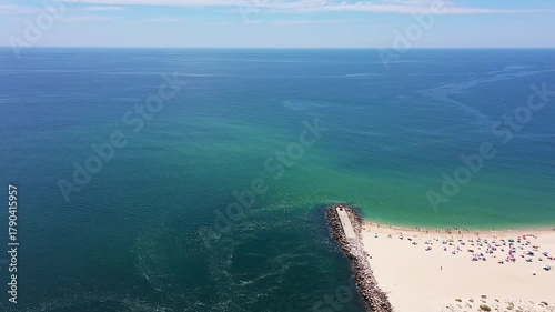 Aerial view drone shot of Tavira Portugal Algarve Aerial view jetty and water vivid turquoise and deep blue currents, small boat moored near sandbar, subtle algae swirls in channel, boater