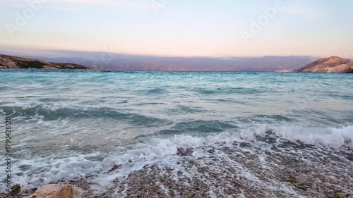 Beautiful waves on a pebble beach at sunset. Baška, Krk Island, Croatia