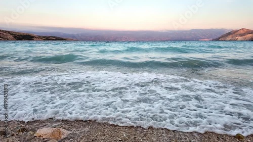 Beautiful waves on a pebble beach at sunset. Baška, Krk Island, Croatia