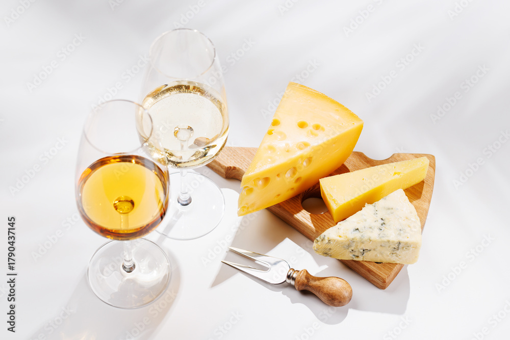 Naklejka premium Assorted cheeses and wine glasses on white background