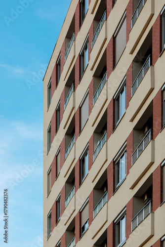 Modern residential building facade with repeating balconies against a blue sky.
