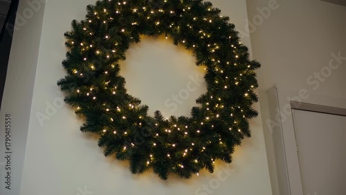 Festive Christmas Wreath Adorned with Sparkling Lights on a Wall.