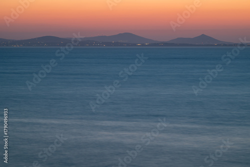 Serene Ocean Sunset with Distant Mountains