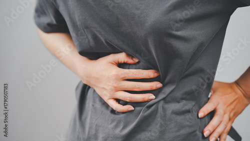 Close-up of a person clutching their side, experiencing abdominal or kidney pain, suggesting health or internal organ issues.