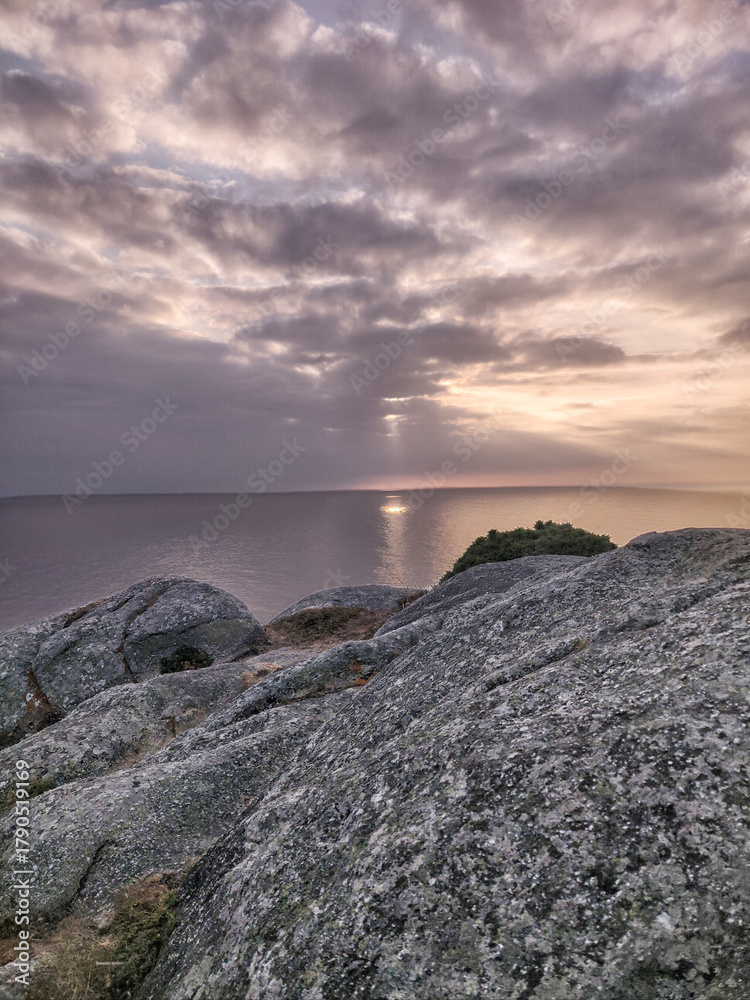 Fototapeta premium Rocky coastline at sunset with sun rays over ocean
