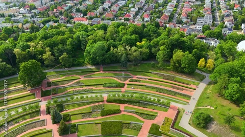 Green urban park revealing residential Poznan neighborhood with colorful houses red rooftops church and tree lined streets on sunny summer day