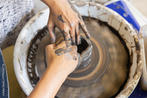 Close up of woman’s hands shaping clay on pottery wheel in selective focus. Handmade ceramic art, artisan craft, traditional pottery process, creative hobby and detailed craftsmanship.