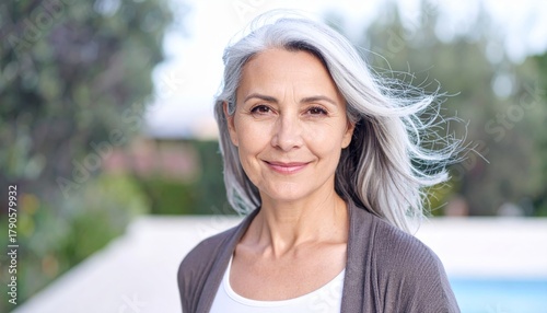 Elegant mature woman with gray hair smiling under natural sunlight. Concept of beauty, wellness, and positive aging.