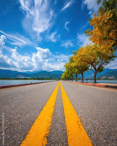 Scenic road stretching toward mountains under a blue sky with white clouds low angle perspective in Vietnam