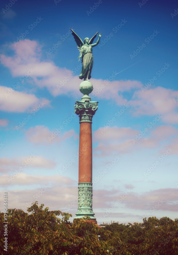 Fototapeta premium Victoria statue on the admiral Ivar Huitfeldt Column (1886) against a cloudy blue sky in Copenhagen, Denmark
