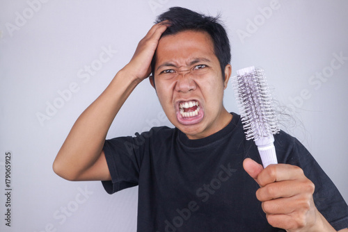 Papier peint Annoyed asian man holding comb, problem hair, hair loss