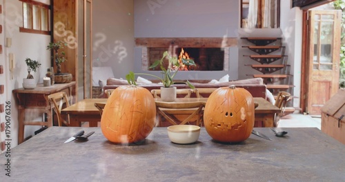 Sitting two carved jack-o'-lanterns glowing on dark island in rustic home, with bowl and knife