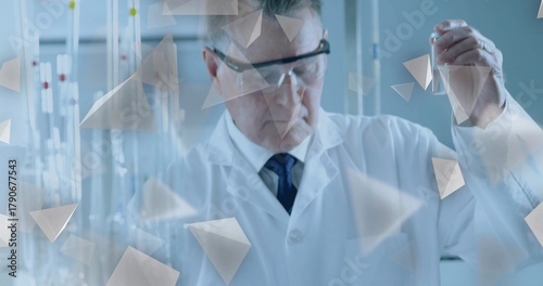 Holding test tube, scientist examining solution at lab bench with burettes, lab coat and goggles