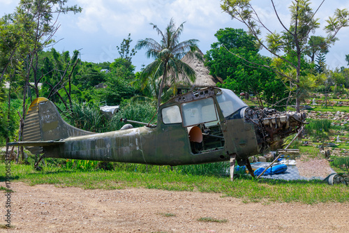 Abandoned Military Helicopter Wreckage and Engine on Display Near Thatched Huts