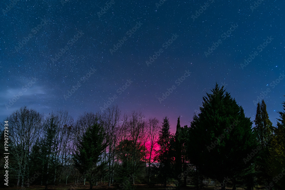 Fototapeta premium Star filled night sky illuminated by the bright magentas of the Aurora Borealis over the Dordogne region of France