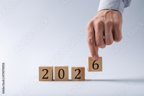 New 2026 year. Man putting cube with number 6 on light grey background, closeup