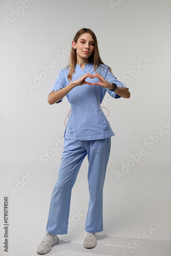 Konstfotografi Young caucasian female nurse in scrubs making heart gesture
