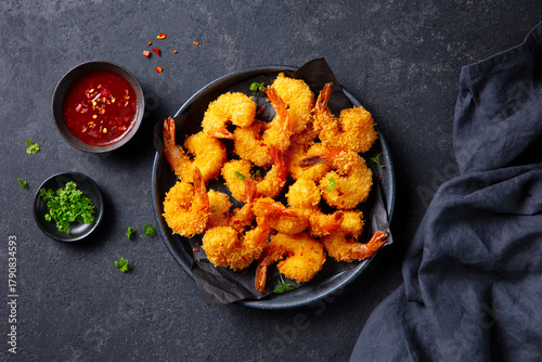 Shrimp tempura with chili sauce on a black plate. Dark background. Close up. Top view.