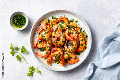 Grilled shrimps with chimichurri sauce on a white plate. Light grey background. Close up. Top view.