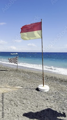 Flags in the wind, fluttering flags in a strong sea breeze in sunny weather on the shore of a seaside resort