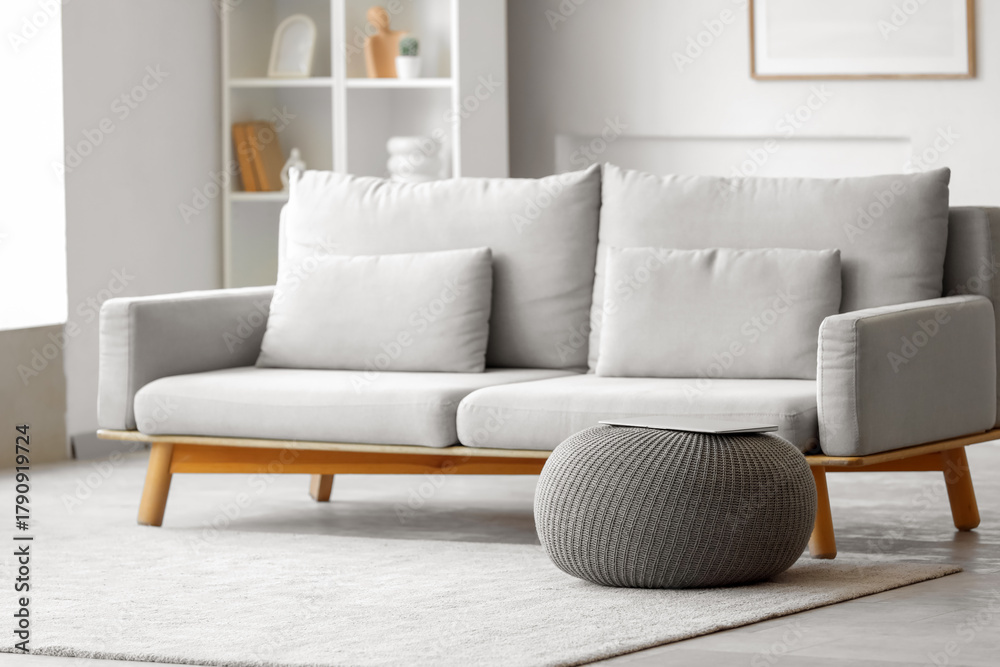 Naklejka premium Laptop on grey pouf in living room interior