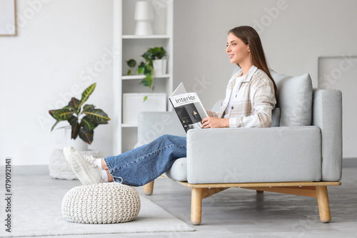 Bild auf Leinwand Young woman reading magazine on sofa with pouf in living room