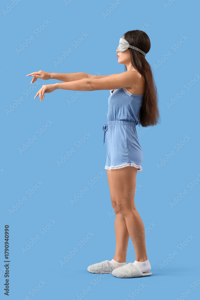 Obraz premium Female sleepwalker in pajamas on blue background