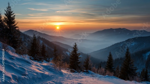 Breathtaking winter landscape with golden orange sunset breaking through clouds over misty mountain valleys, snow-dusted slopes with silhouetted evergreen spruce trees, blue sky, peaceful atmosphere.