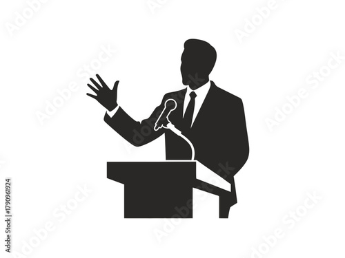 A silhouetted figure stands at a podium speaking into a microphone.