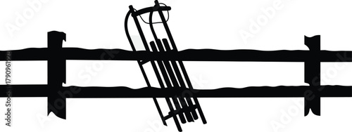 A resting sled leaning against a fence, a winter scene of leisure and relaxation