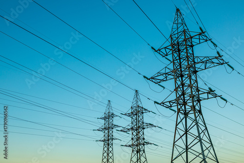 Three tall power lines are in the sky, with a blue sky in the background