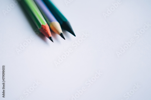 Close-up macro shot of three sharpened colored pencils on a clean white background, creating a minimalist concept for education, art, or starting a new idea