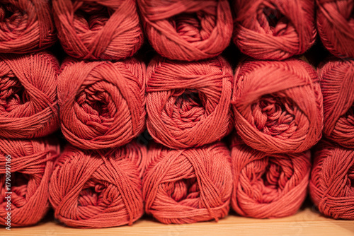 Neatly stacked red yarn skeins in store display.
