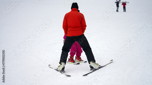 A ski slope. An instructor conducts a skiing lesson with a small child.