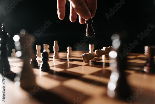 A hand lifts a dark king from the board as a white king lies down; narrative image of reversal, capture and the closing act of play.