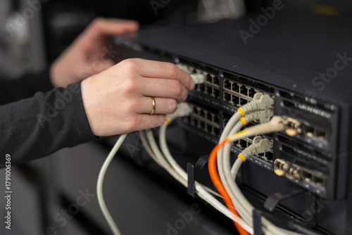 Fotografie Female IT technician in a datacenter connecting and configuring network switches