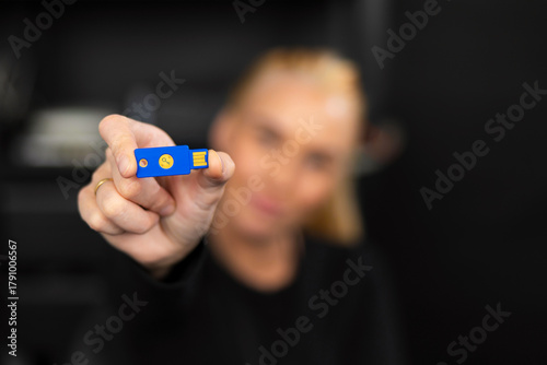 Caucasian woman IT security technician in a tech office holding a blue USB flash drive for data security
