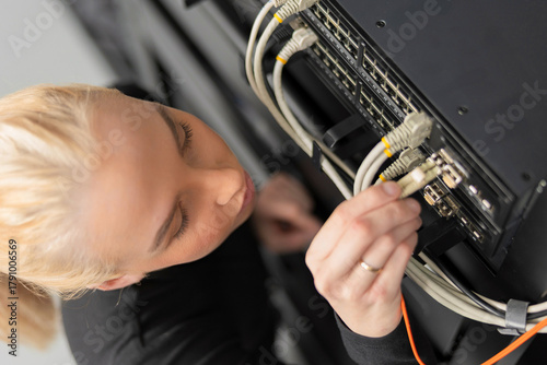 Female IT technician in her 20s working on network equipment in a data center