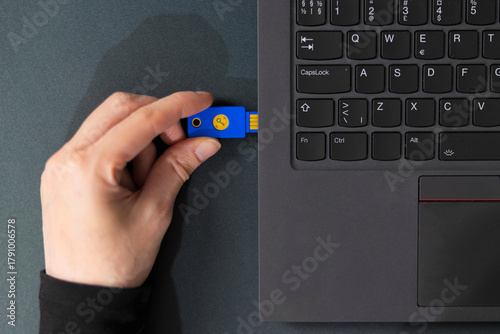 IT security technician using a USB flash drive beside a laptop in a tech office